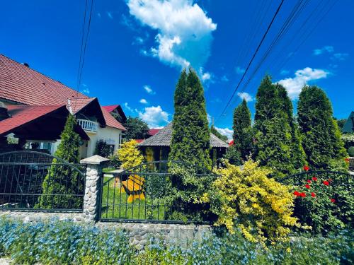 a fence in front of a house with trees at Pensiunea Irina Maramureș in Deseşti