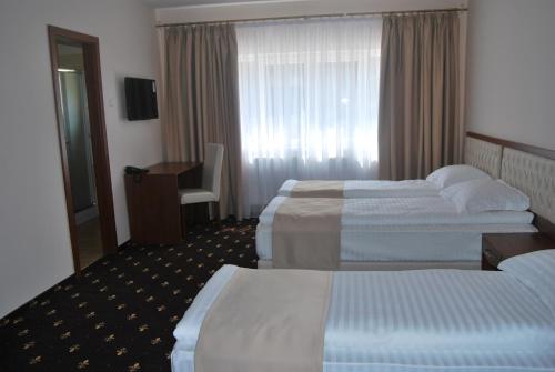 a hotel room with two beds and a desk at Hostel Paltinis in Hunedoara