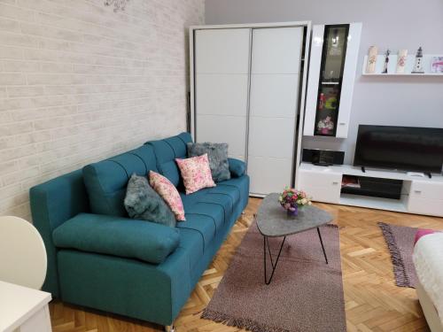 a living room with a blue couch and a tv at Apartment "GARDEN" on Gundulićeva 8 in Novi Sad