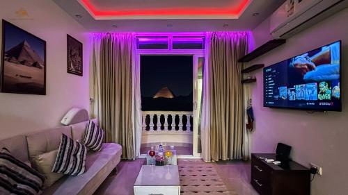 een woonkamer met een bank en een tv bij Queen Pyramids View Apartment in Caïro