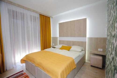 a bedroom with a bed with a yellow blanket at Hotel - Villa Lejla in Mostar