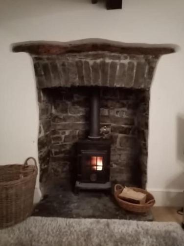 a stone fireplace in a room with a basket at Bridge View Victorian Townhouse Central Aberystwyth Sleeps 6 in Aberystwyth