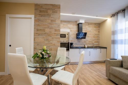 a dining room and kitchen with a glass table and white chairs at Apartamentos La Jasa in Arguedas