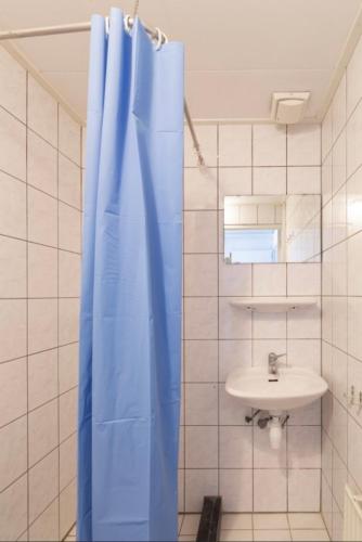 een badkamer met een blauw douchegordijn en een wastafel bij Vakantiebungalow Bisschops in Simpelveld