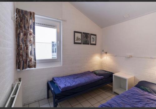 een slaapkamer met een bed en een raam erin bij Vakantiebungalow Bisschops in Simpelveld