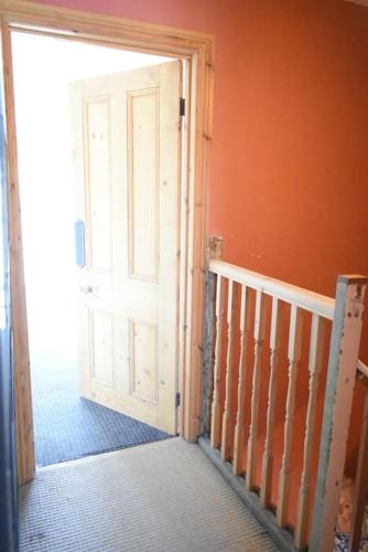 an orange room with a door and a staircase at Bridge View Victorian Townhouse Central Aberystwyth Sleeps 6 in Aberystwyth