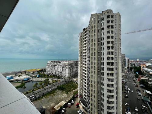 a tall building next to the ocean and a city at My Sunshine Apartments in Batumi in Batumi