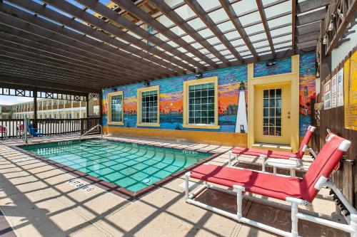 a swimming pool with two chairs and a mural at Lighthouse Inn in South Padre Island