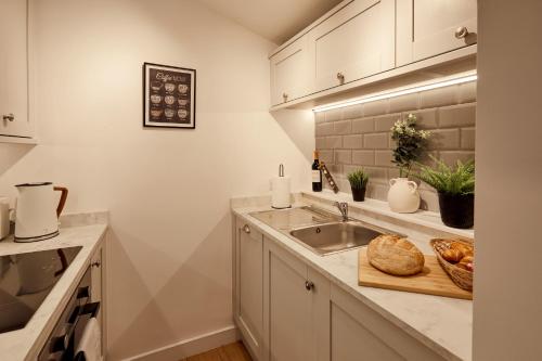 eine Küche mit einer Spüle und einem Schneidebrett mit Brot in der Unterkunft Norton Studio in Arundel