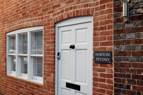 a white door and two windows on a brick building at Norton Studio in Arundel