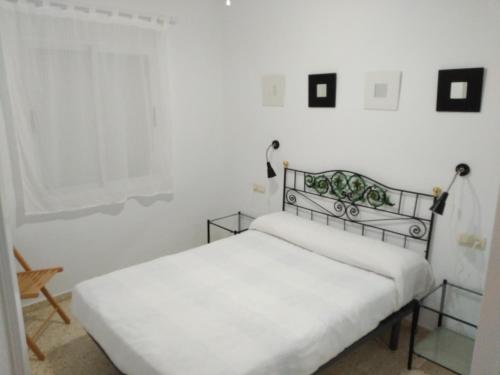 a white bedroom with two beds and a window at Apto para Vacaciones con WIFI in Chipiona