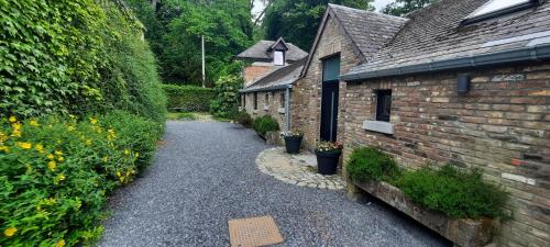 a path between two brick buildings with flowers at L'arche De Noé in Dinant