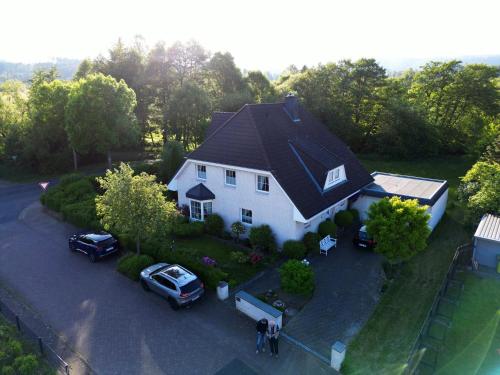 a white house with cars parked in a driveway at Pension Roseneck in Wolfshagen