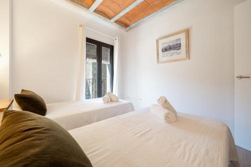 two beds in a white room with a window at Hauzify I Apartaments Montblanc in Montblanc
