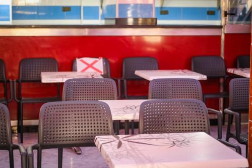 an empty restaurant with tables and chairs with a red wall at Hotel EL MARSA LA PLAYA in Laayoune