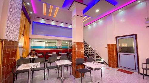 a restaurant with tables and chairs and a staircase at Hotel EL MARSA LA PLAYA in Laayoune