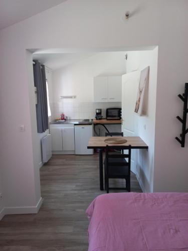 a room with a table and a kitchen with white cabinets at COQUETTE MAISONNETTE in Bourges