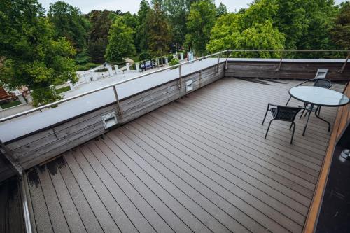 a wooden deck with a table and chairs on a balcony at Gabija Hotel SPA & Conferences in Palanga