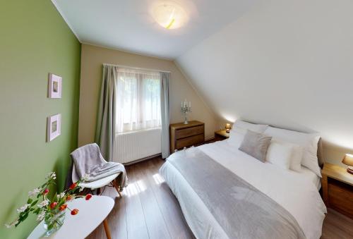 a bedroom with a large white bed and a chair at Hanga Vendégház in Tihany