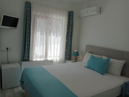 a bedroom with a bed with a blue pillow and a window at Daffne Otel in Canakkale