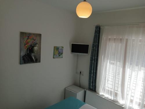 a bedroom with a bed and a television and a window at Daffne Otel in Canakkale