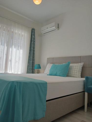 a bedroom with a bed with blue pillows and a window at Daffne Otel in Canakkale