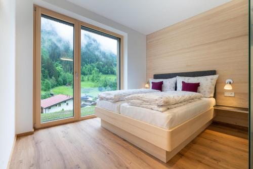 ein Schlafzimmer mit einem Bett und einem großen Fenster in der Unterkunft Apartment Fitsch in Silbertal