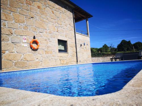 a swimming pool in front of a stone building at Casa Borlido in Ponte de Lima