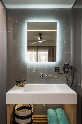 a bathroom with a white sink and a mirror at Alkionides Seaside Hotel in Plataniás
