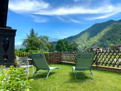 trois chaises assises dans l'herbe dans une cour avec une clôture dans l'établissement Enjoy Ledro B&B, à Ledro