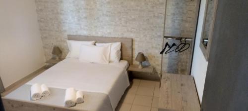 a small bedroom with a white bed with slippers on it at Poseidon room's Vourvourou in Vourvourou