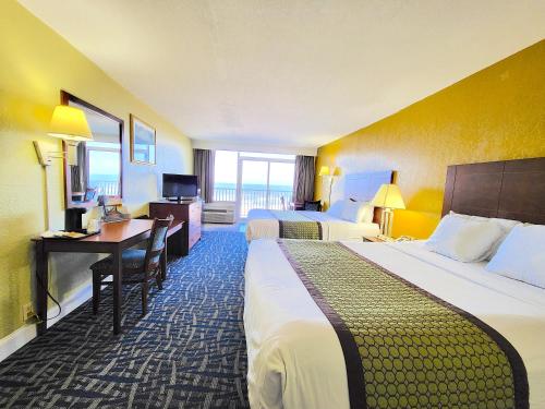 a hotel room with two beds and a desk at Ocean Resort in Virginia Beach