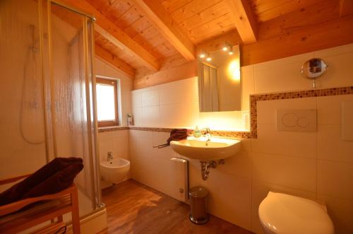 ein Badezimmer mit einem Waschbecken, einem WC und einem Spiegel in der Unterkunft Feriendorf Via Claudia Haus 53 Alpenrose in Lechbruck