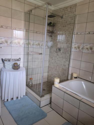 een badkamer met een douche, een bad en een tafel bij Cheerful Family Holiday Home in Brakpan