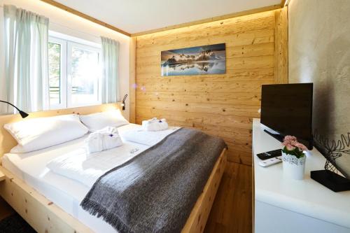 een slaapkamer met een bed met een houten muur bij Mäxle Apartments in Bad Hofgastein