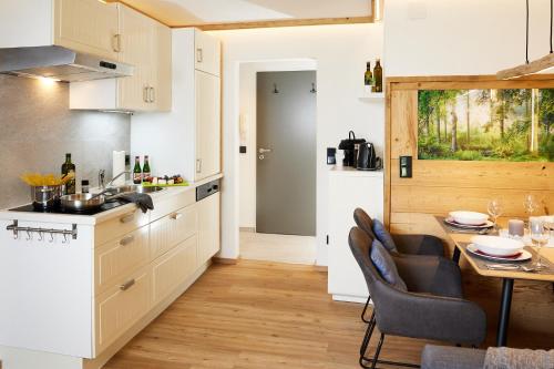 - une cuisine et une salle à manger avec une table et des chaises dans l'établissement Mäxle Apartments, à Bad Hofgastein