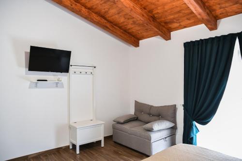 a bedroom with a couch and a tv on a wall at ATHENA in Scilla