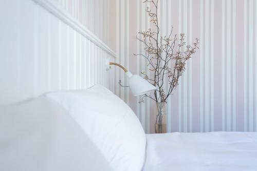 a white bed with a lamp and a vase with flowers at Melsted Badehotel in Gudhjem