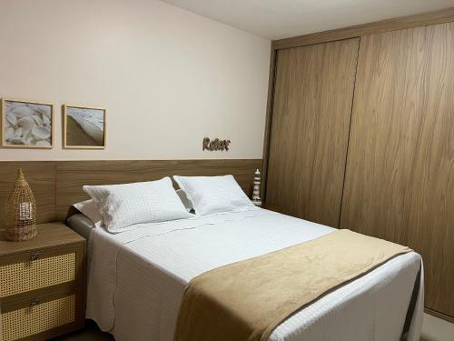 a bedroom with a large bed and a wooden cabinet at Maiorca - Mar & Lazer 3 suítes Itacimirim pé na ar in Itacimirim