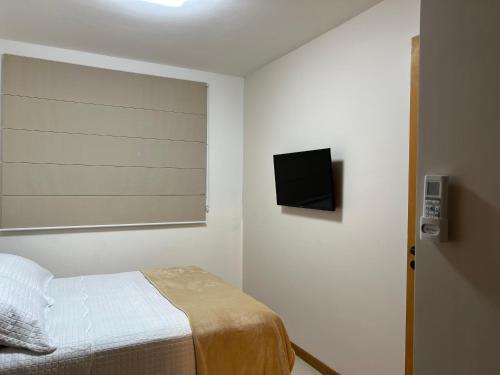 a bedroom with a bed and a television on the wall at Maiorca - Mar & Lazer 3 suítes Itacimirim pé na ar in Itacimirim