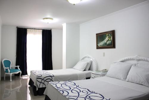 a hotel room with two beds and a chair at Hotel Suite Santa Rosa in Santa Rosa de Cabal