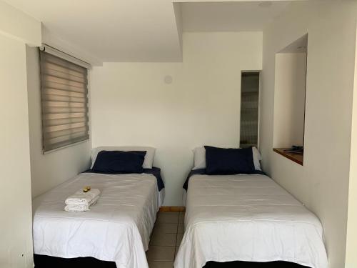 two beds in a room with white sheets and blue pillows at Alquiler temporario Mendoza in Mendoza