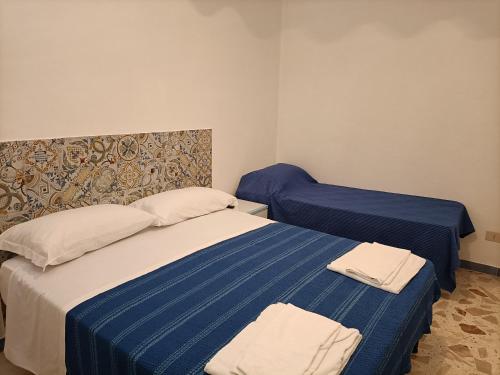a bedroom with two beds with blue and white sheets at La casetta a Scopello in Scopello