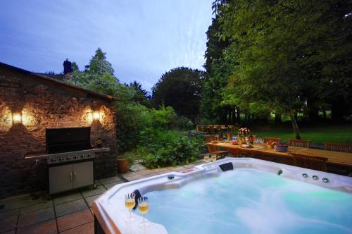 una gran bañera de hidromasaje en un patio con patio en Topside House - Beautiful 7 bedroom house with hottub wifi and parking near Bath Wells Frome, en Oakhill