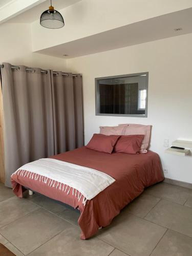 een slaapkamer met een groot bed met rode lakens en kussens bij « La Parenthèse » gîte en Camargue in Arles