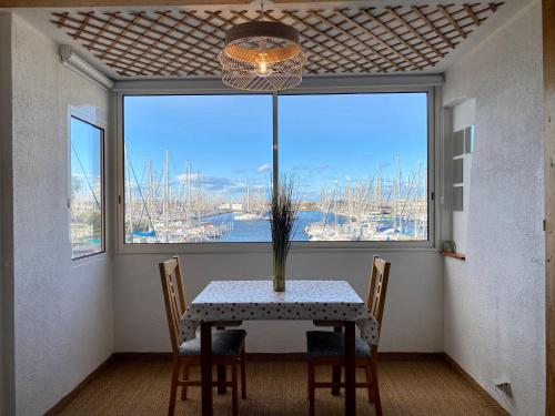 uma sala de jantar com uma mesa e uma grande janela em LE COCON DE LA MARINA em Leucate