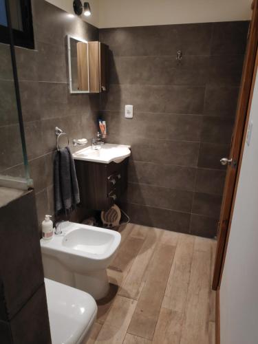 a bathroom with a white toilet and a sink at Cabaña El Trisquel in Villa Serrana