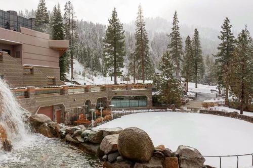 a snow covered pool in front of a building with a waterfall at Resort at Squaw Creek in Olympic Valley