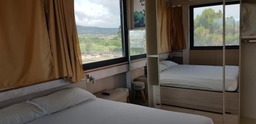 two beds in a room with two windows at Suite Panorama - attico esclusivo con vista Etna e Ionio in Riposto