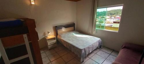 a small bedroom with a bed and a window at Magic Island Casas in Florianópolis